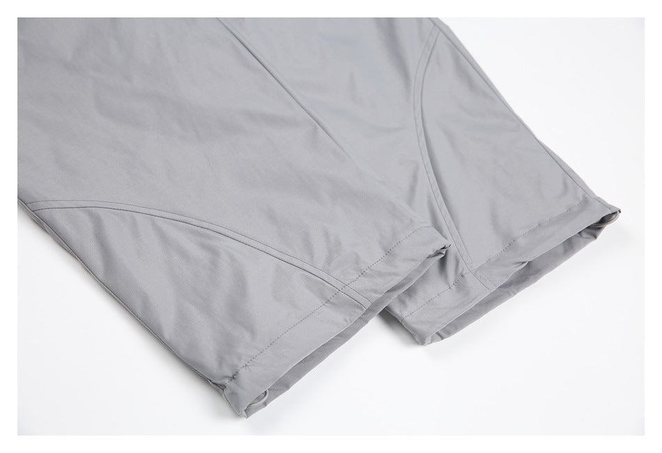 Close-up of the stitched hems and panel seams on gray pant legs.