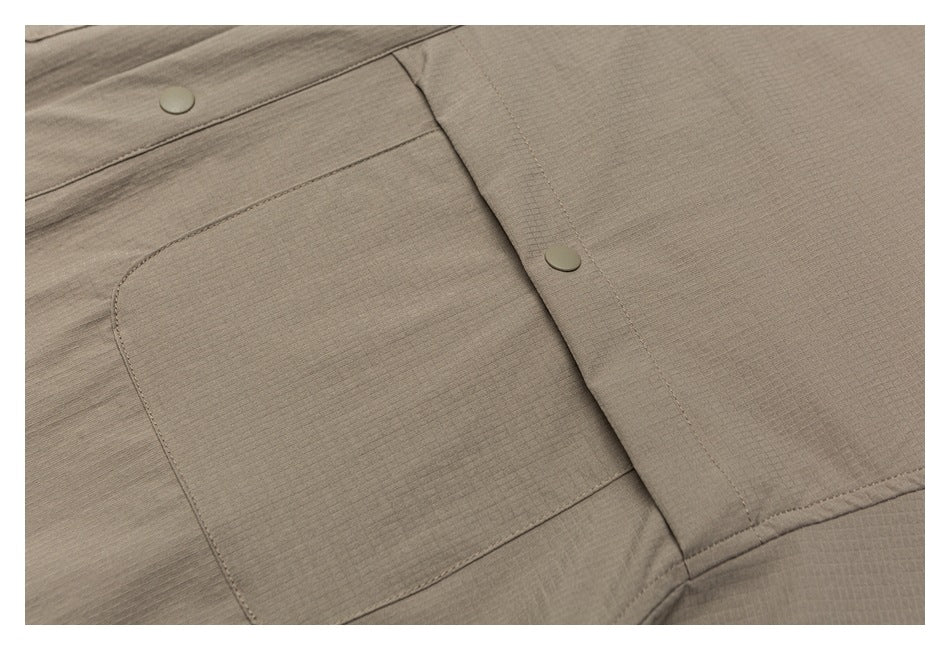 Close-up of a taupe shirt's chest pocket and front placket with matching buttons.