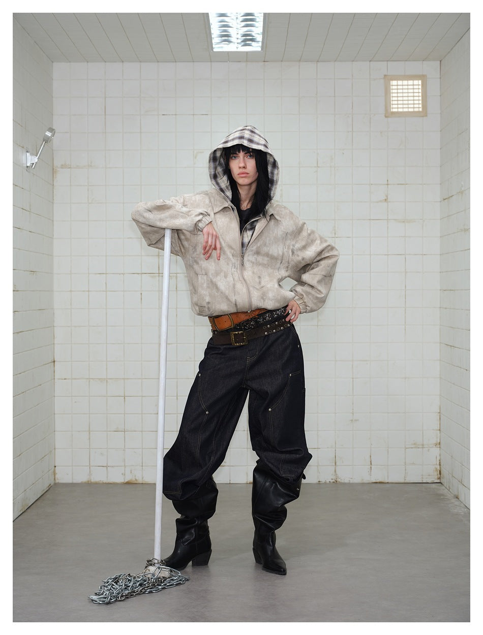 Model wearing a light beige mottled zip jacket with a plaid hood, dark baggy jeans and black boots.