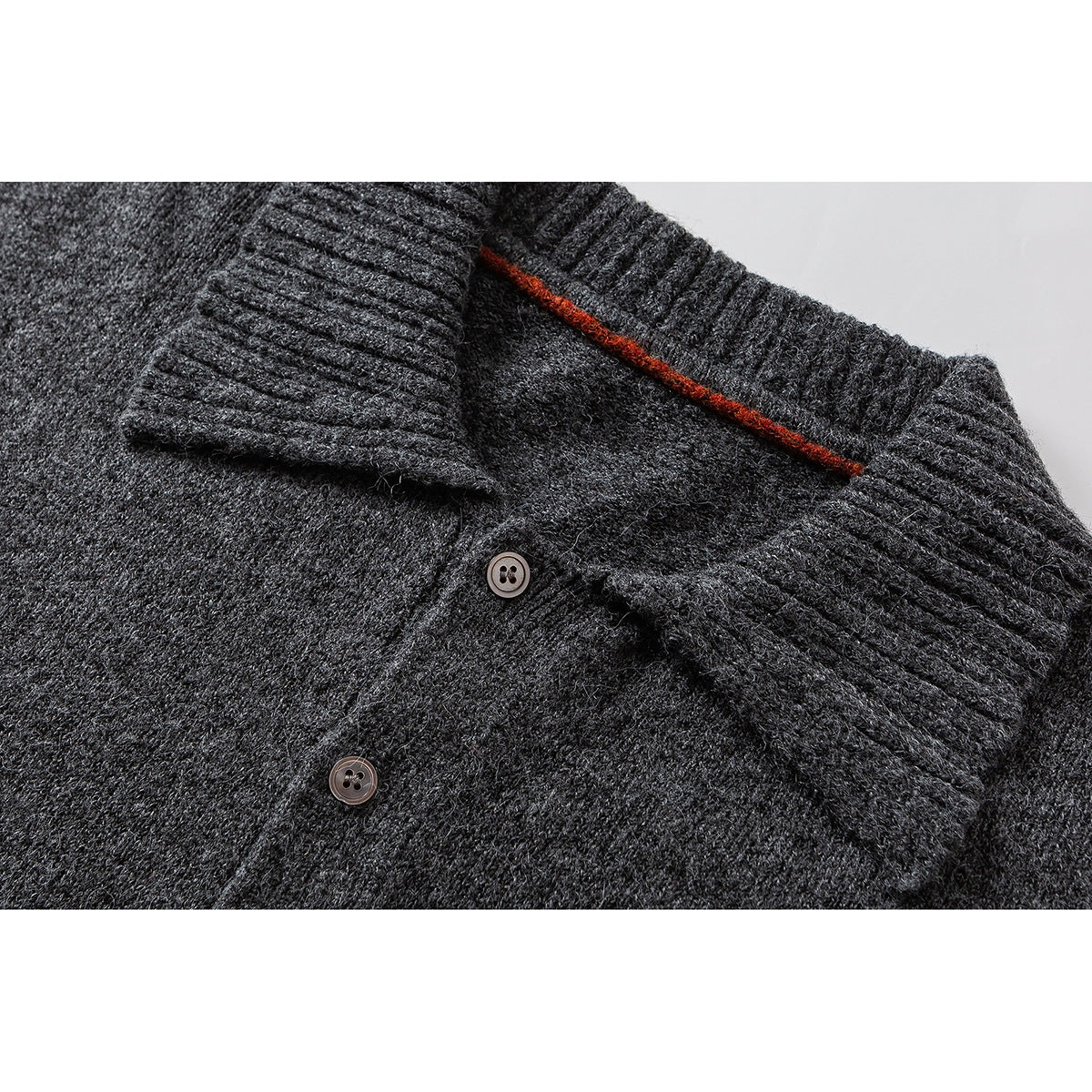 Close-up of a charcoal knit sweater's ribbed collar, button placket, and rust-colored inner trim.
