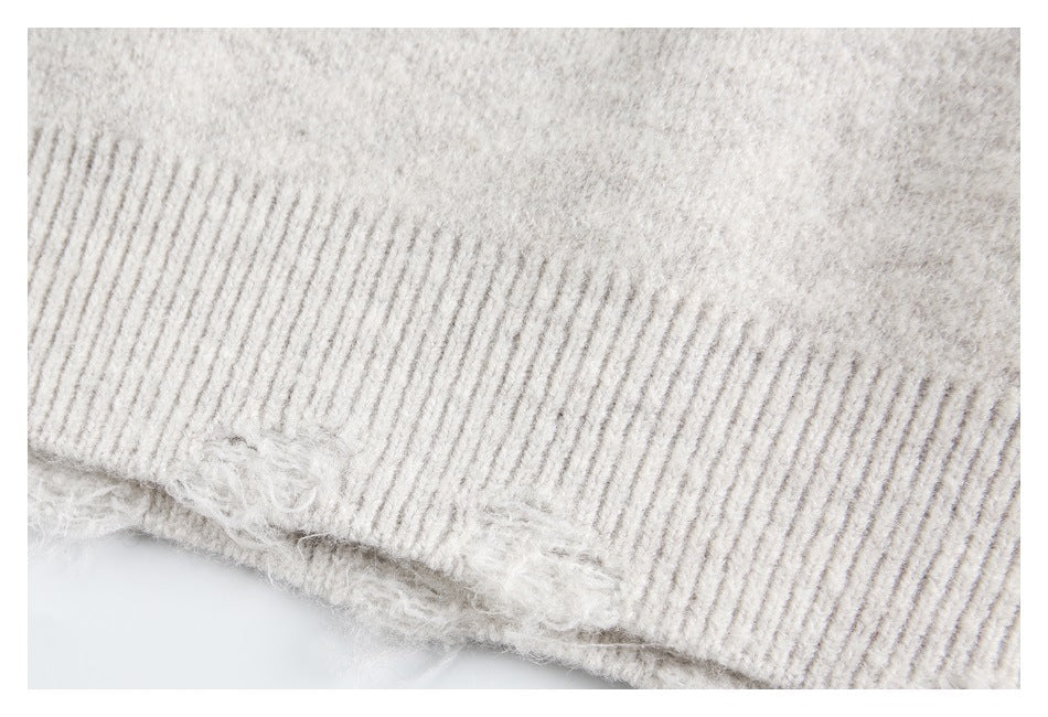 Close-up of the light gray sweater's ribbed hem with loose, fuzzy fibers along the edge.