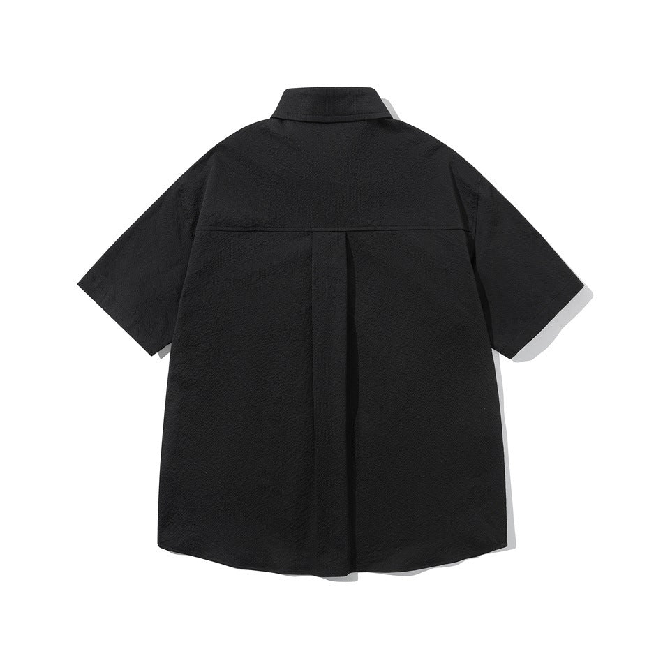 Back view of a black short-sleeve button-up shirt with a center pleat and yoke seam.