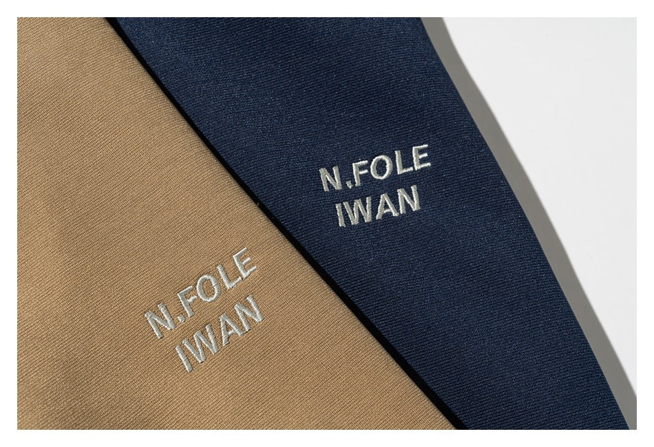 White embroidered lettering on tan and navy garment panels.