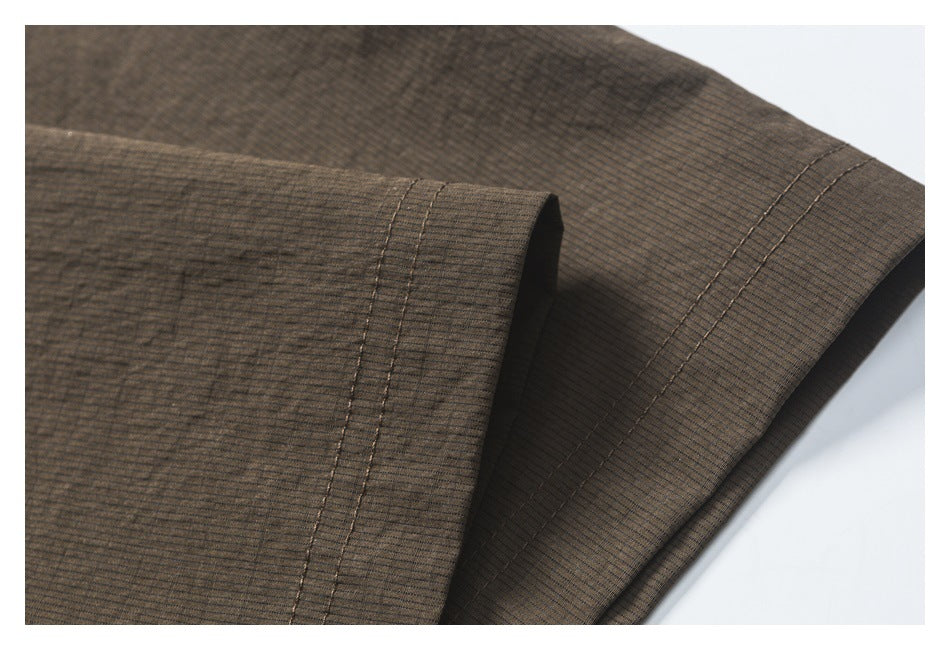 Close-up of a dark brown garment sleeve and double-stitched cuff.