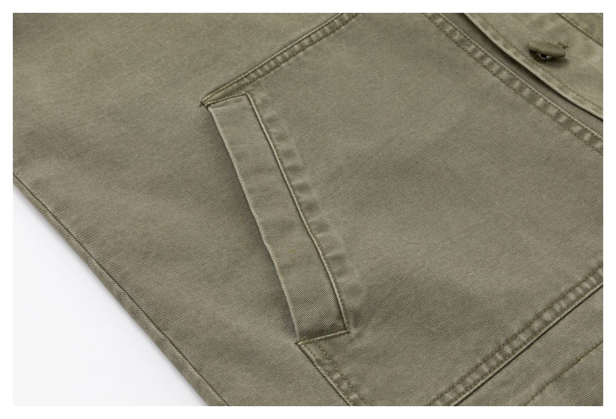 Close-up of a vertical welt pocket and stitching on the olive-gray jacket.