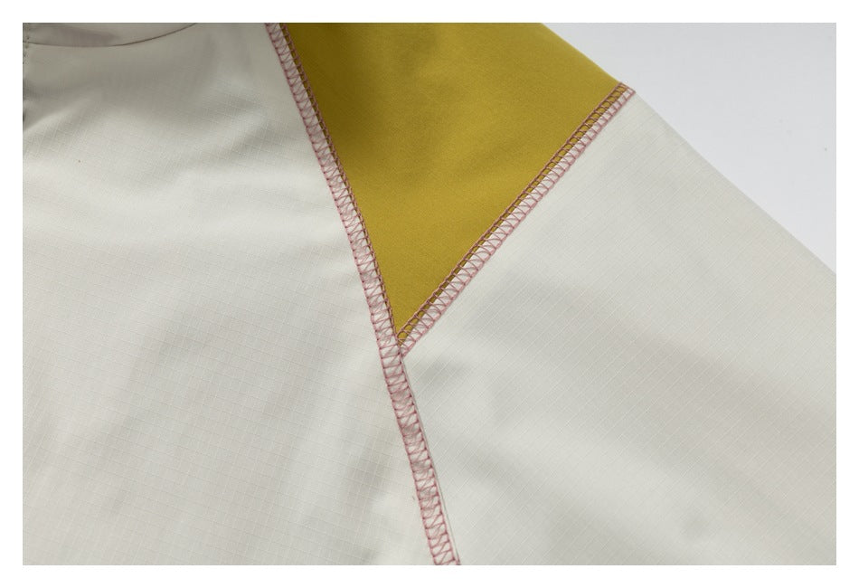 Close-up of cream fabric meeting a mustard-yellow panel, with pink overlock stitching along the seams.