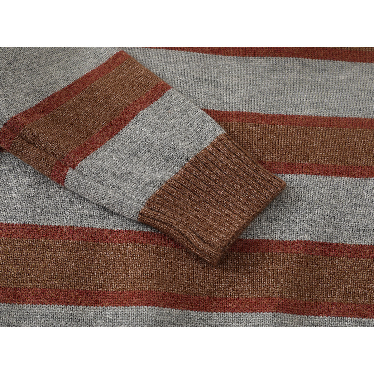 Close-up of a sweater sleeve and ribbed brown cuff, showing brown, rust, and gray stripes.