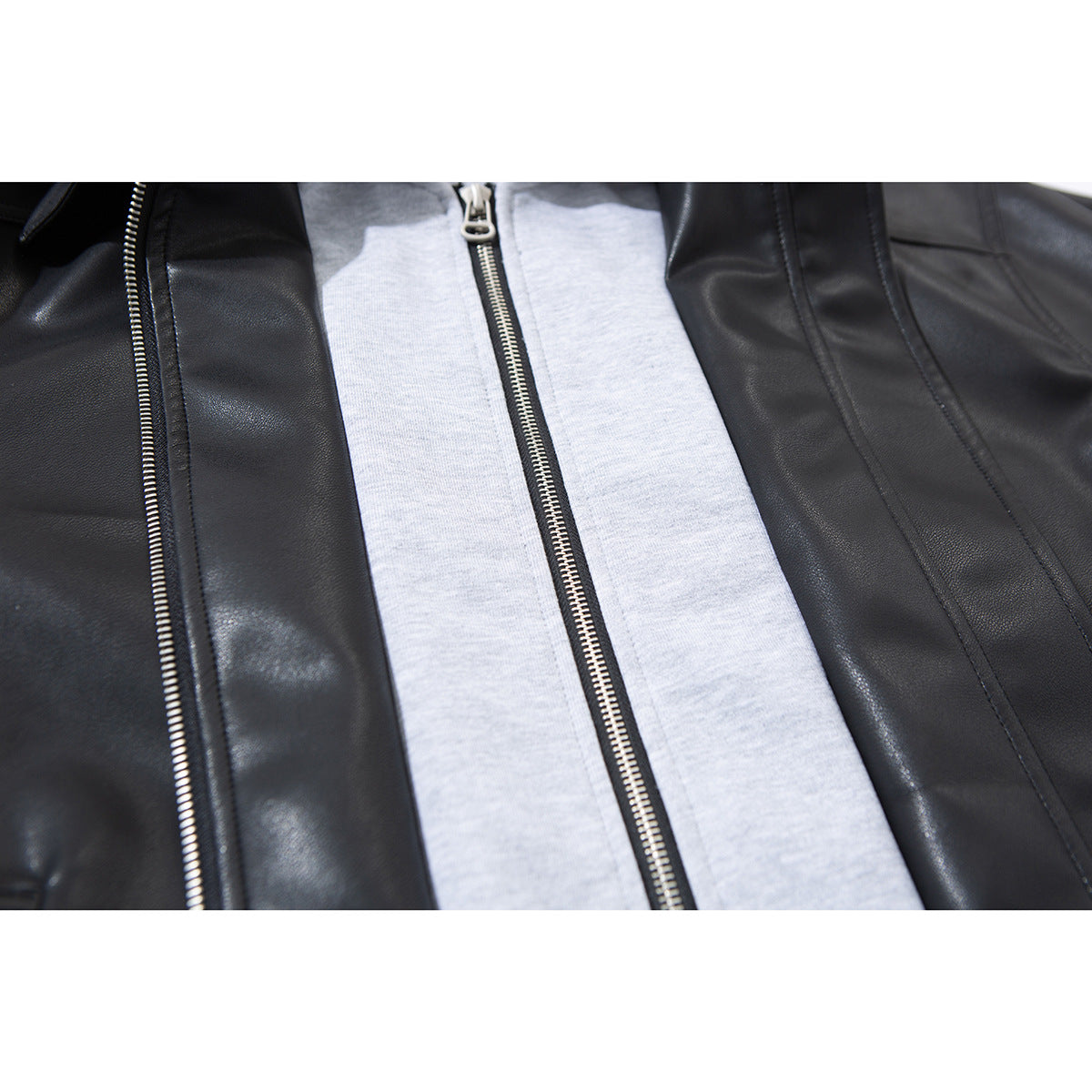 Close-up of a black jacket with a gray center panel and two visible silver zippers.