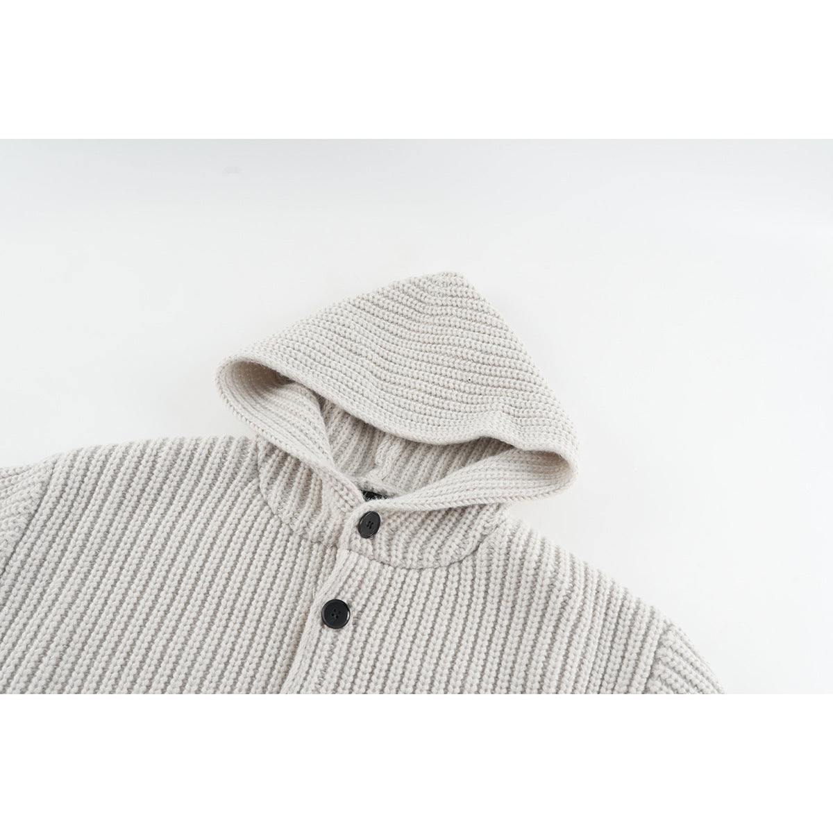 Close-up of an off-white rib-knit hooded cardigan showing the hood, neckline and dark front buttons.