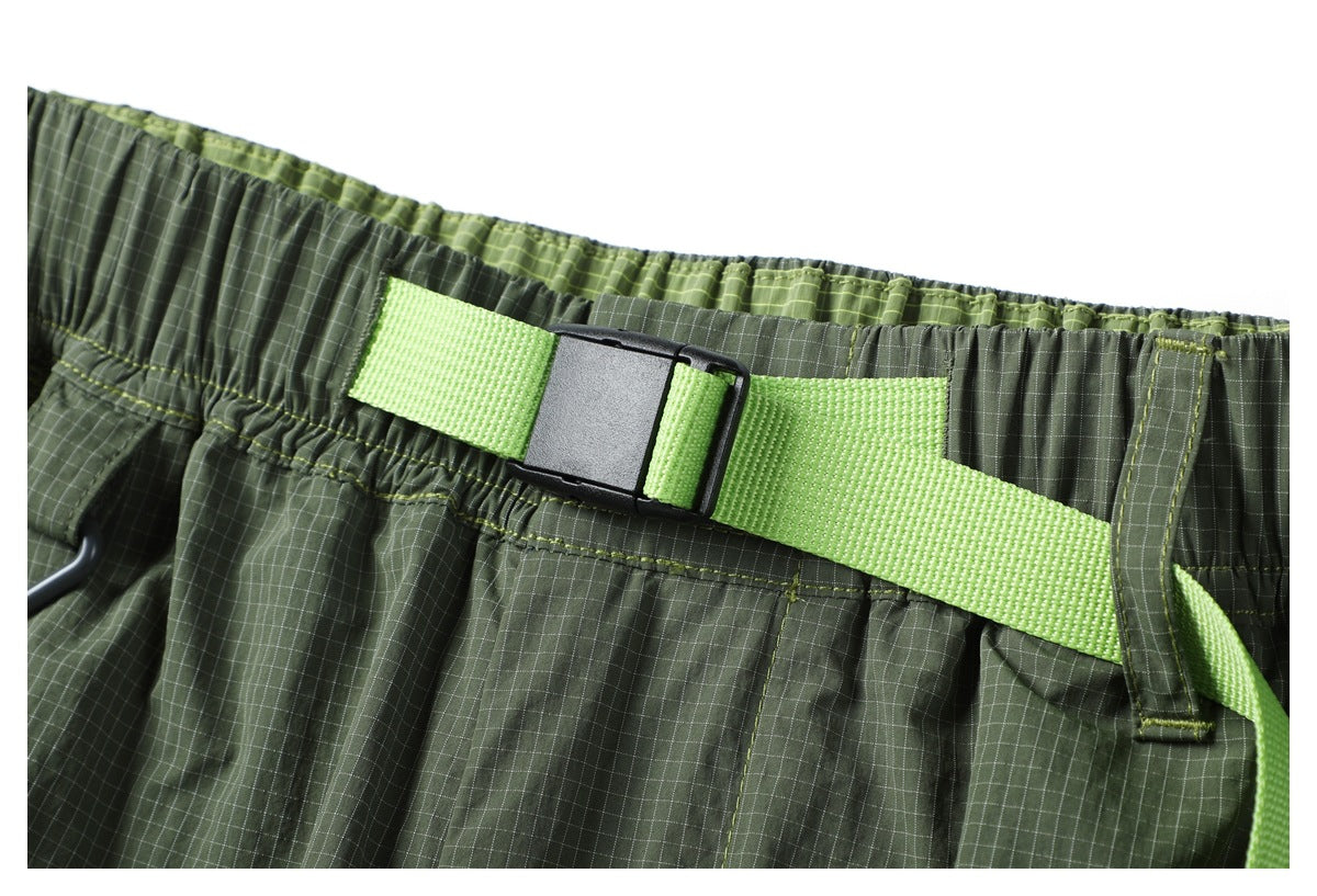 Close-up of the gathered waistband and bright green webbing belt with a black buckle.