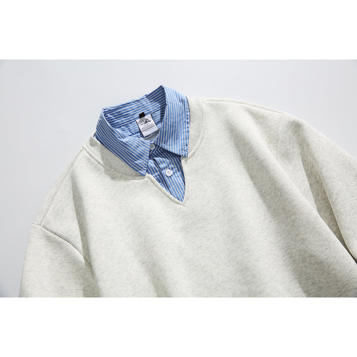 Close-up of a light heather-gray sweatshirt with a blue-and-white striped shirt collar and placket.