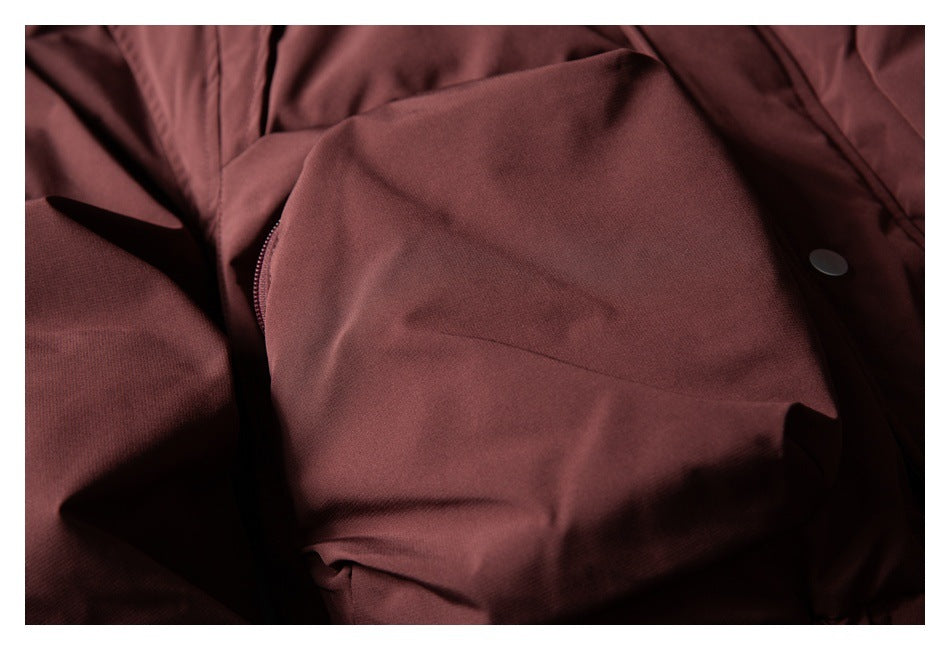 Close-up of a burgundy jacket pocket area with a zipper edge and snap button.