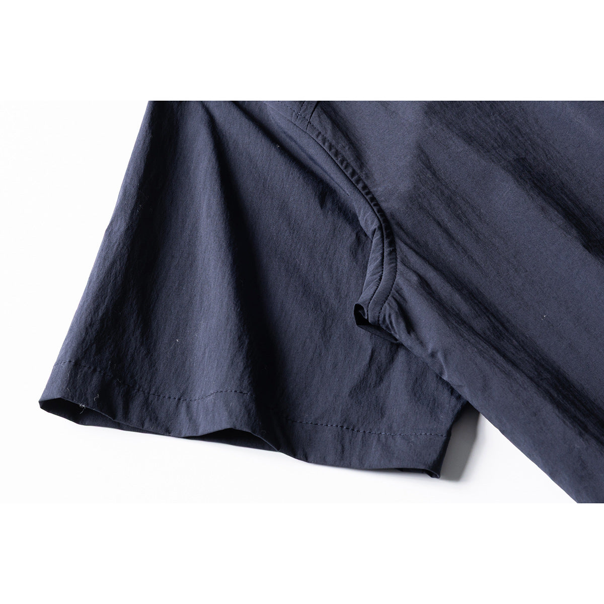 Close-up of the navy shirt's short sleeve, hem stitching, and underarm seam.