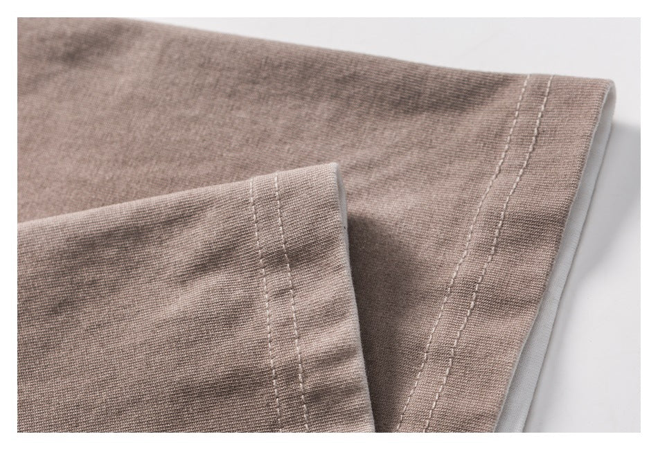 Close-up of double-stitched hems on folded taupe T-shirt fabric.