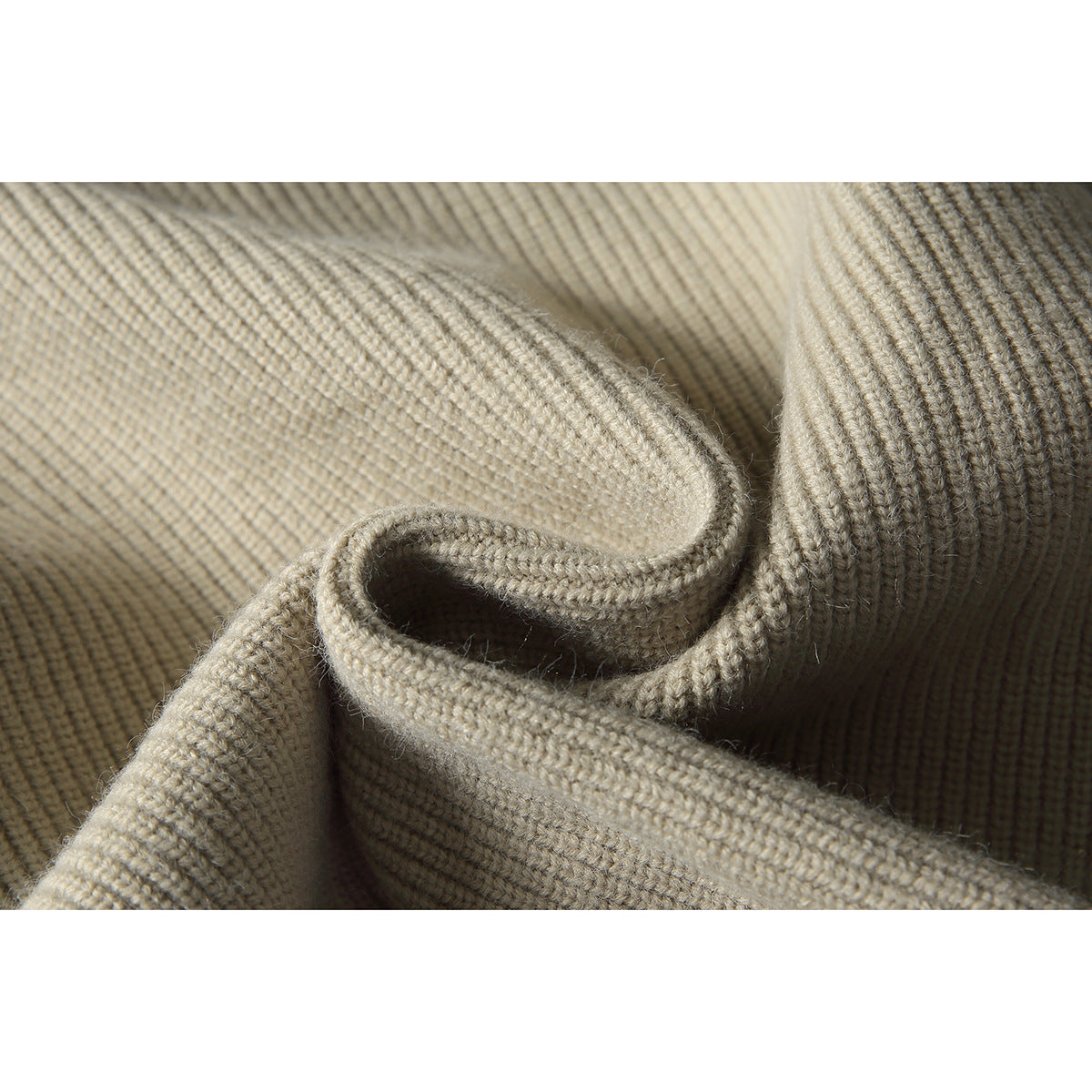 Close-up showing the beige sweater's ribbed knit texture and folded edge.