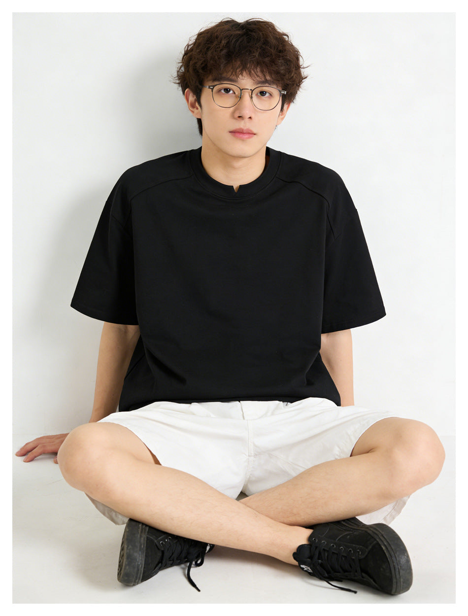 Seated model wearing a black short-sleeve crew-neck T-shirt, shown from the front.