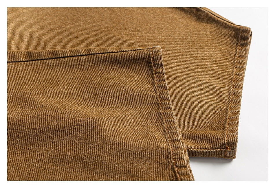 Close-up of tan trousers showing a large patch pocket and a stitched leg hem.