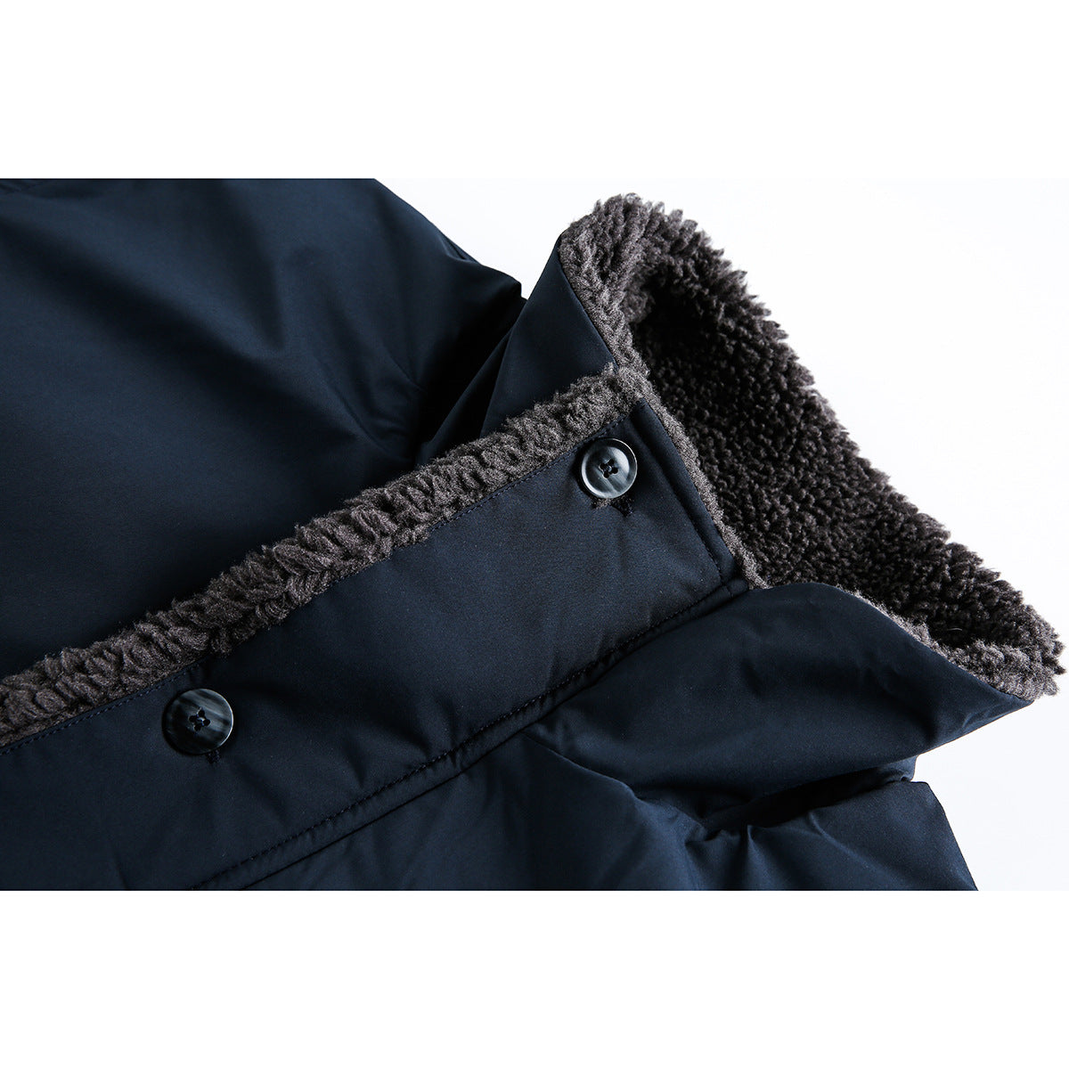 Close-up of a dark navy coat showing charcoal fuzzy lining along the edge and two dark buttons.