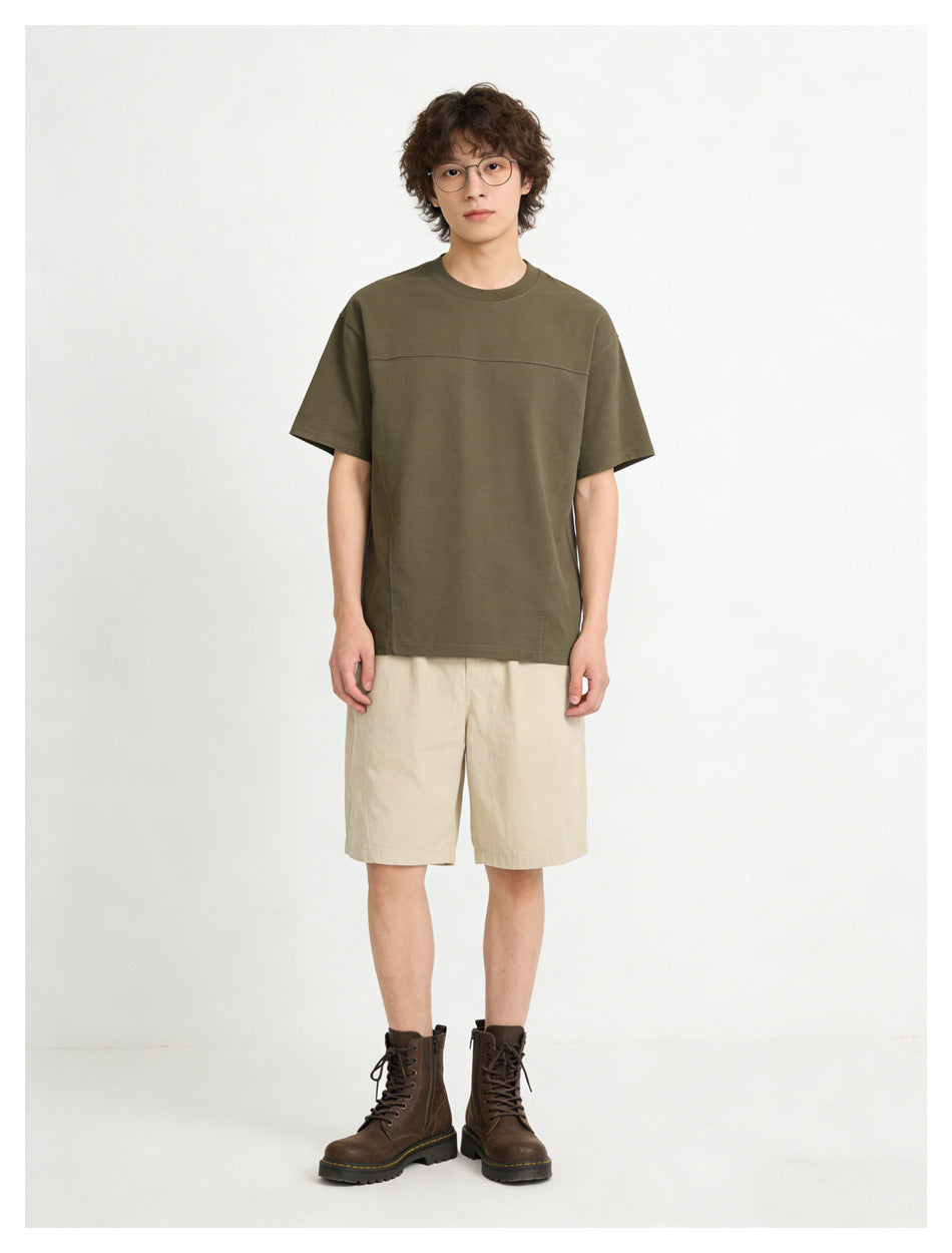 Front view of a model wearing an olive short-sleeve crew-neck T-shirt with a horizontal chest seam and beige shorts.