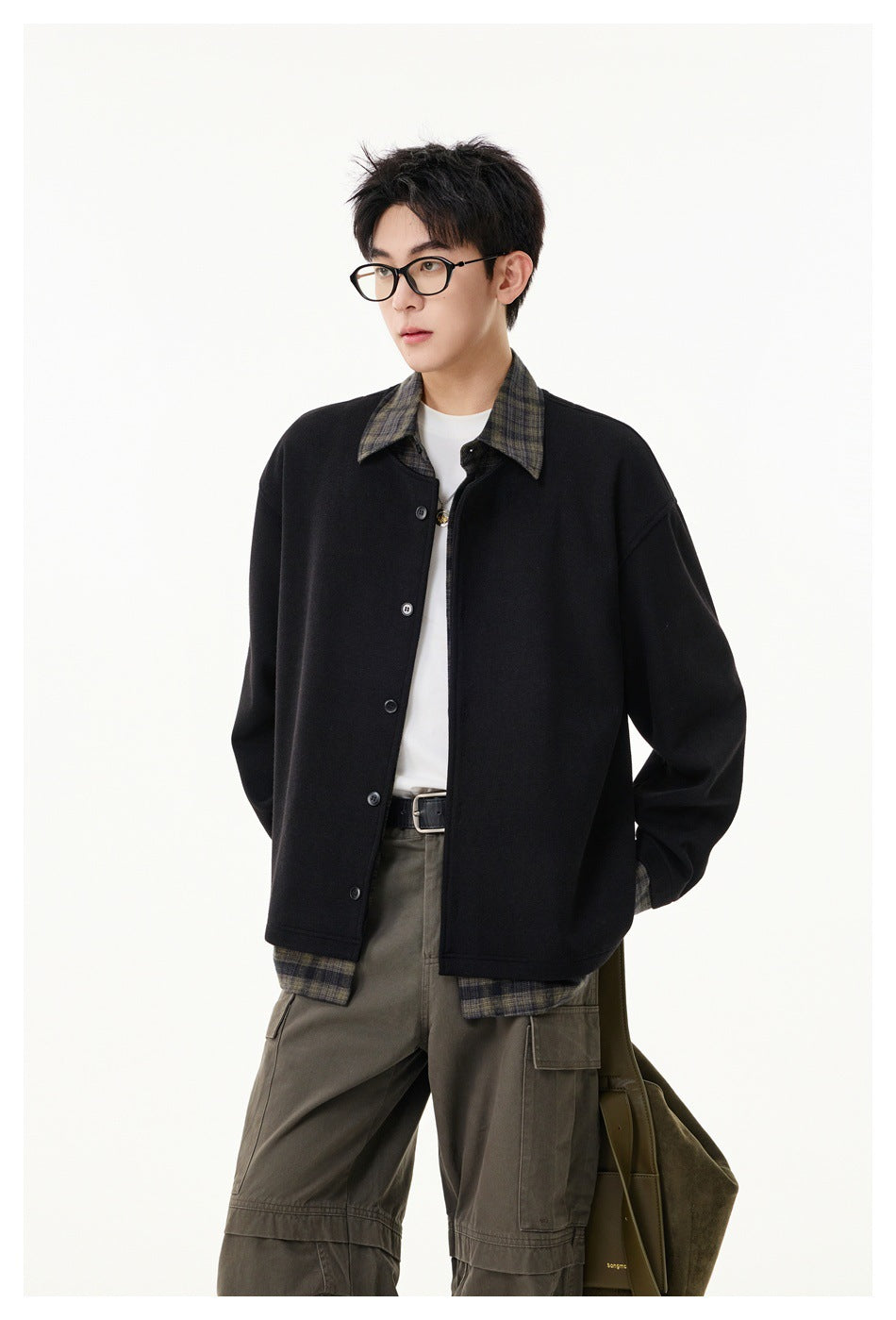Model wearing a black button-front jacket with plaid collar and hem over a white tee and olive cargo pants