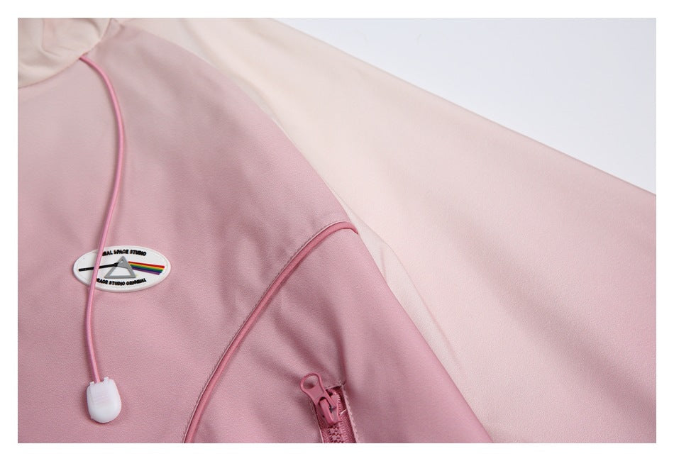 Close-up of a pale pink jacket sleeve and shoulder seam with a small oval patch and drawcord.