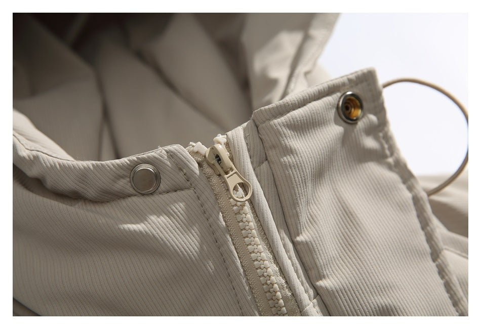 Close-up of a beige ribbed jacket's front zipper, zipper pull, and metal snap fasteners.
