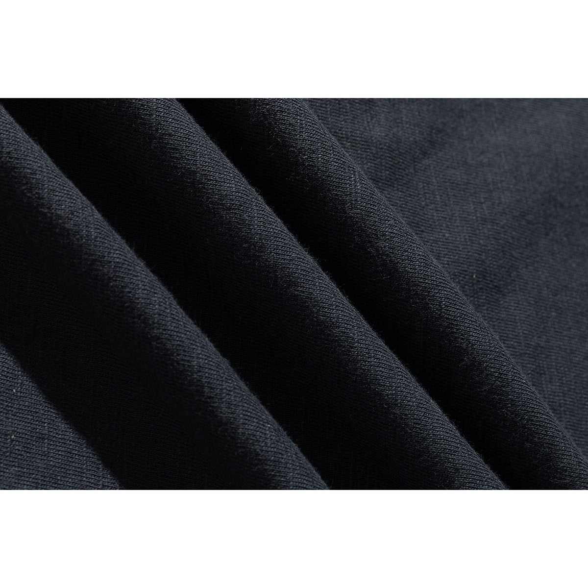 Macro view of dark knit T-shirt fabric draped in folds.