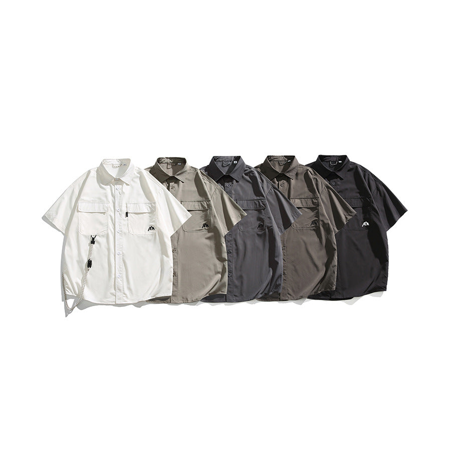 Five short-sleeve button-up shirts with chest pockets shown in white, beige, charcoal, taupe, and black.