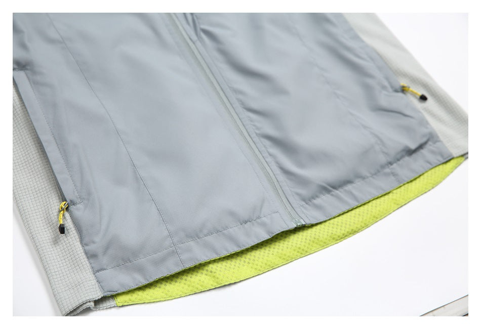 Close-up of the gray jacket's front zipper, lower panels, yellow-trimmed pockets, and lime hem lining.