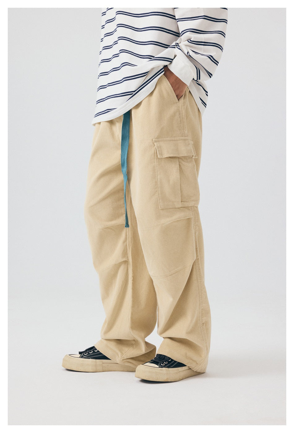 Side view of a model wearing beige cargo pants, showing a flap pocket and long blue drawstring.