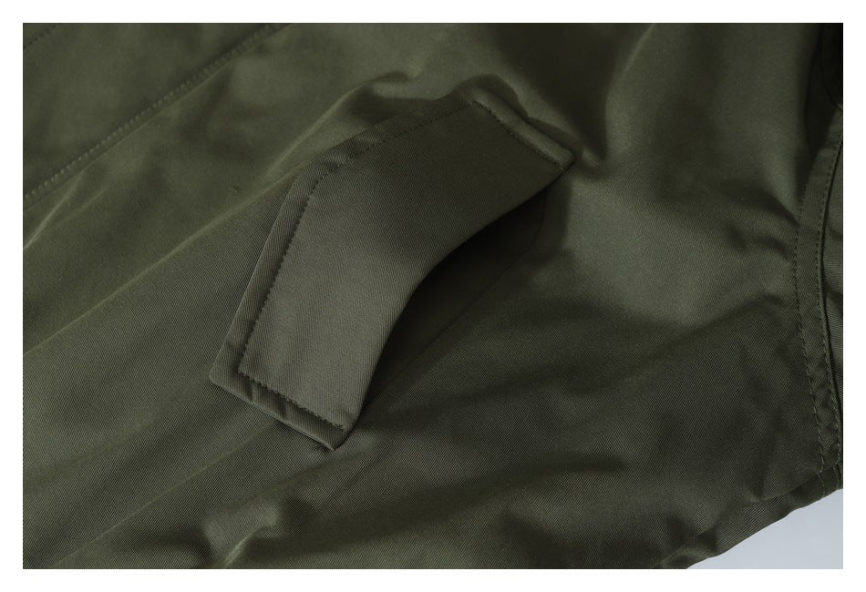 Close-up of a slanted welt pocket on the olive jacket.