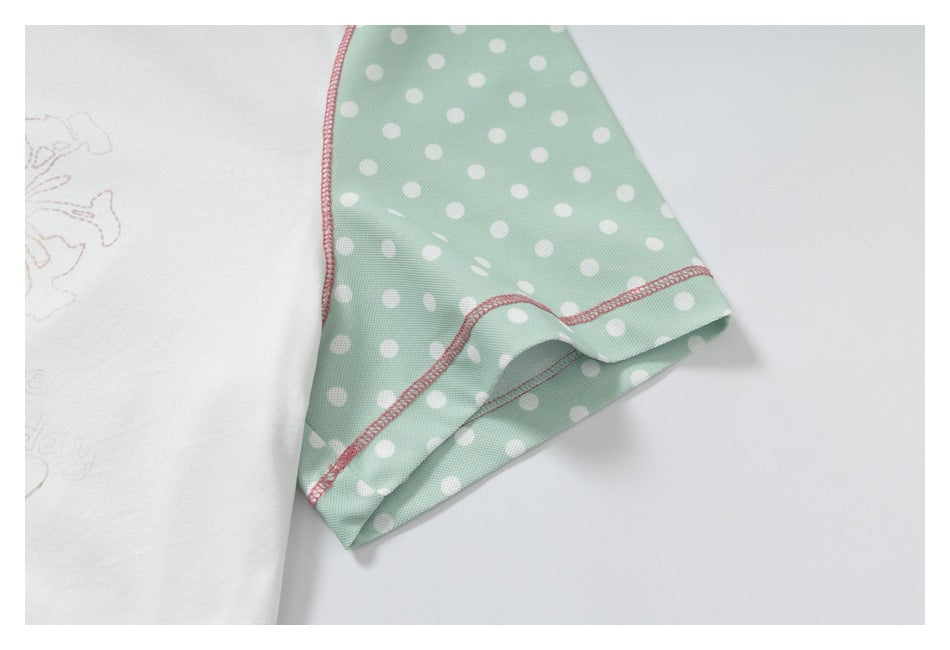 Close-up of the mint-green polka-dot sleeve and pink stitching beside the white shirt body.
