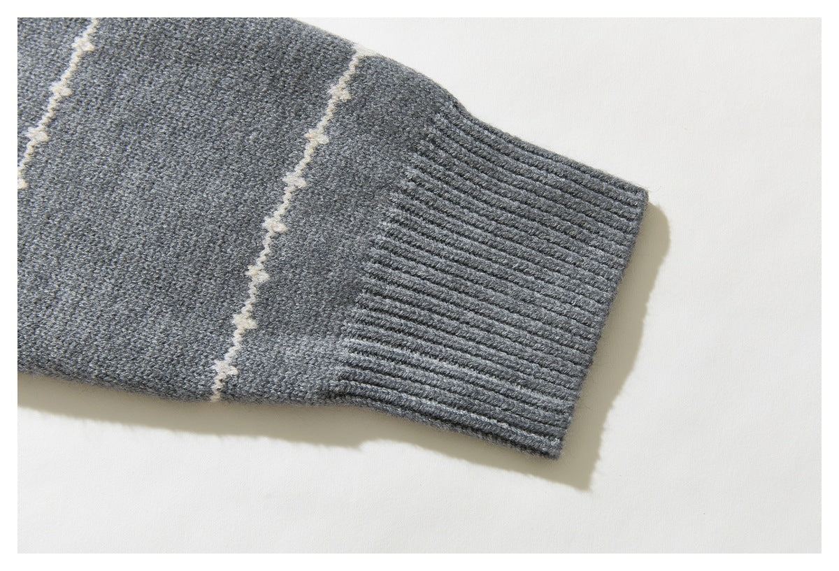 Close-up of a gray sweater sleeve with a cream stripe and wide ribbed cuff.