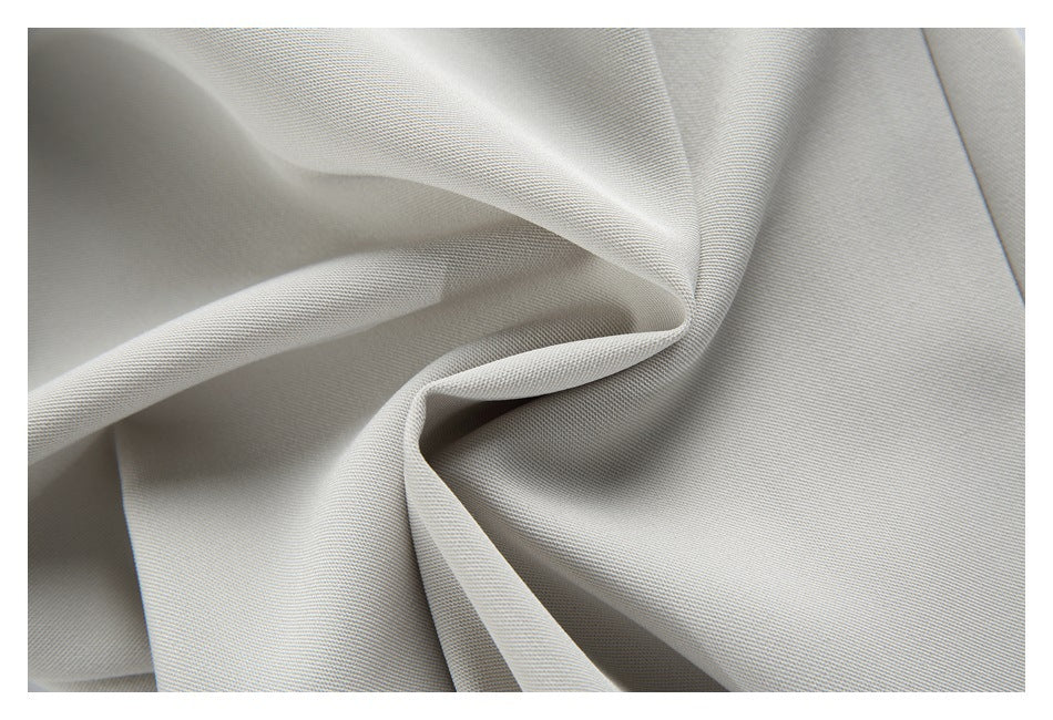 Close-up of light gray woven fabric draped into soft folds, showing a fine diagonal texture.