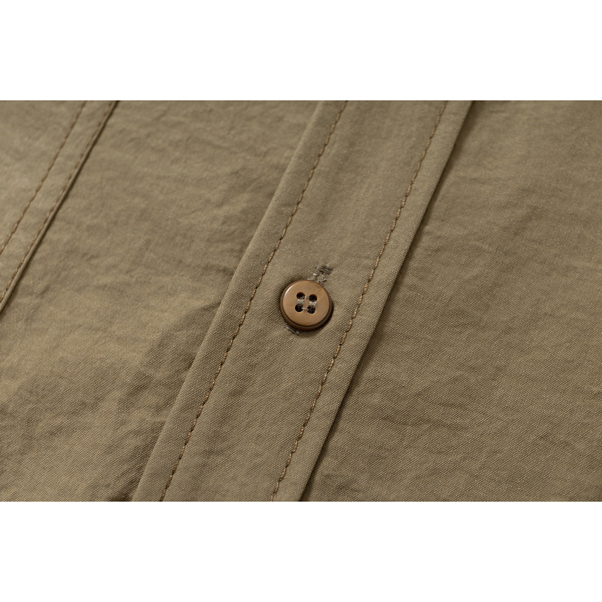 Close-up of a brown button on the tan shirt's stitched front placket.