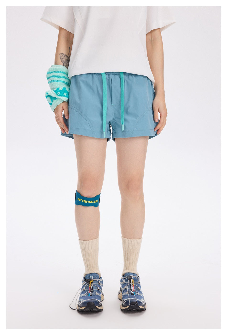 Front view of a model wearing light teal running shorts with turquoise drawstrings and curved front pockets.