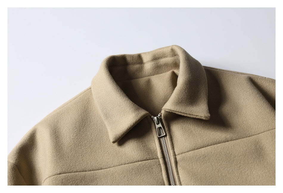 Close-up of a tan jacket's pointed collar, metal front zipper, and upper chest seam.