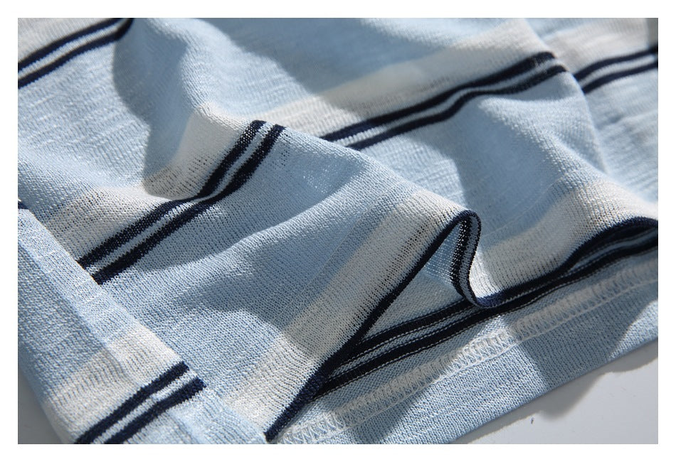Close-up of folded light blue and white striped knit fabric, showing dark navy stripes and the hem stitching.