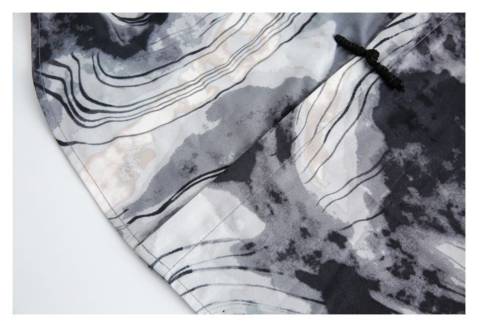 Close-up of the abstract-print shirt's hem and a black knotted frog closure.