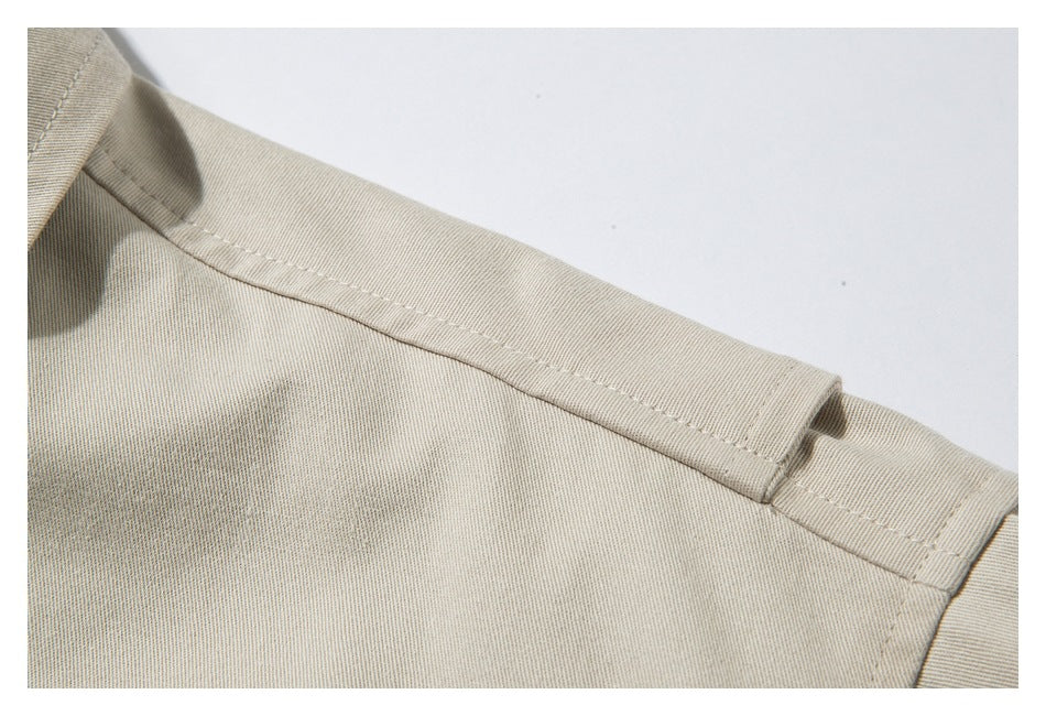 Close-up of a beige jacket shoulder seam and topstitched panel.