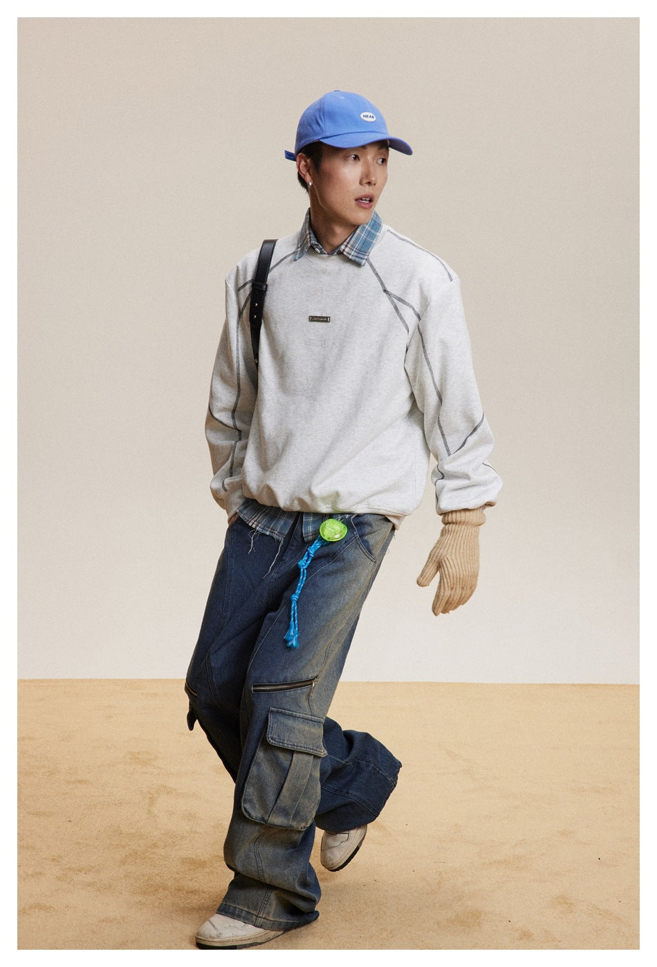 Model in a light gray contrast-stitched sweatshirt and dark cargo jeans, shown in a full-length pose.