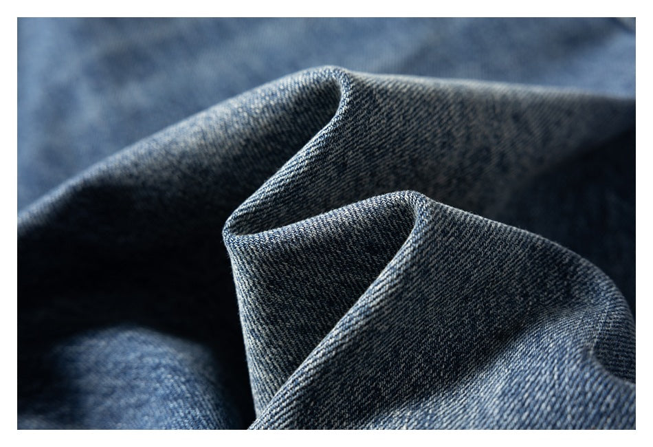 Close-up of dark blue denim fabric folded to show its diagonal weave and texture.