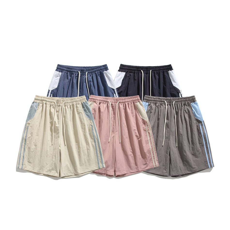 Five pairs of color-block athletic shorts shown from the front in navy, black, cream, pink and gray.