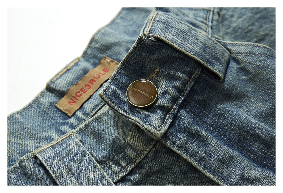Close-up of a blue denim waistband with a metal button, belt loop, and sewn label.