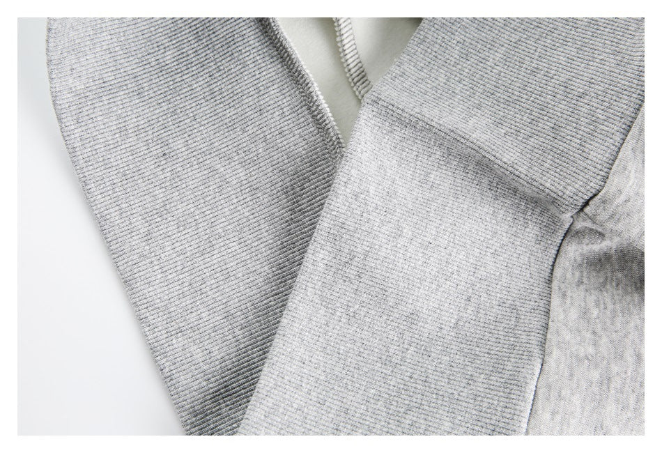 Close-up of a light gray jacket's ribbed sleeve, seam, and open zipper edge.