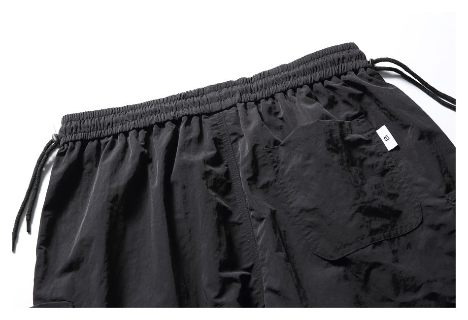 Close-up of black shorts with an elastic drawstring waistband and a flap pocket.