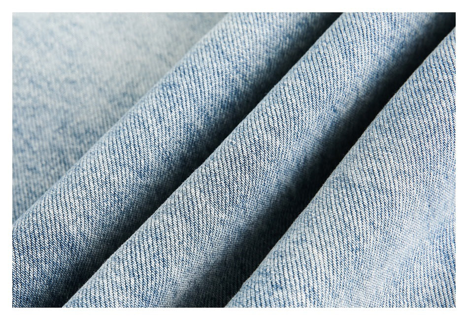 Close-up of light-blue denim fabric arranged in soft folds.