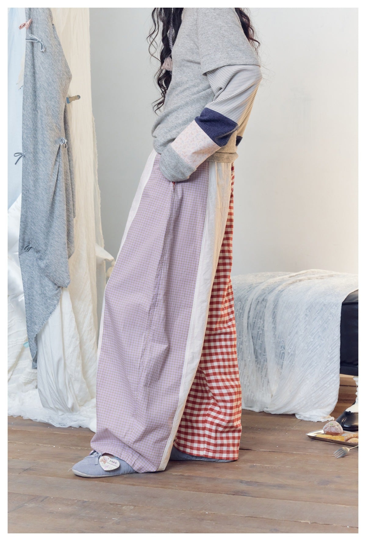 Close side view of a model wearing patchwork trousers with lilac checks, white panels and red gingham.
