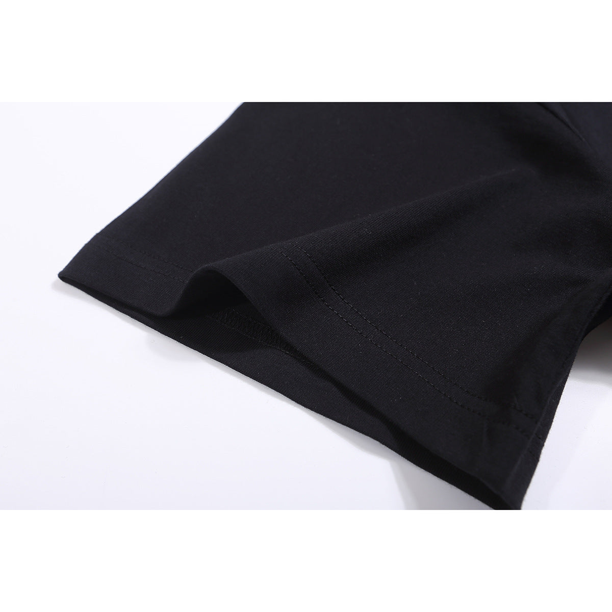 Close-up of the stitched hem and fabric of a black T-shirt.