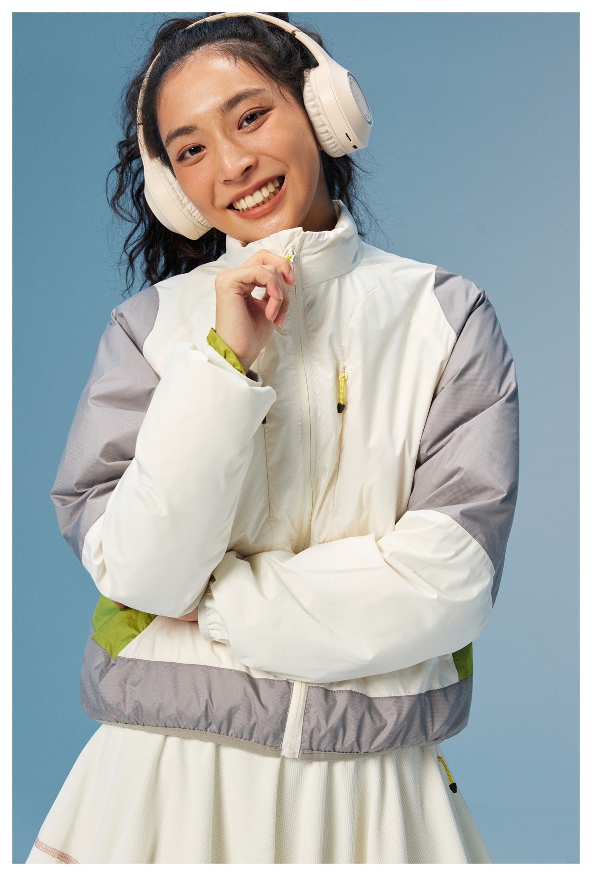 Front view of a woman wearing a white zip jacket with gray sleeves, lime accents, and a gray hem.